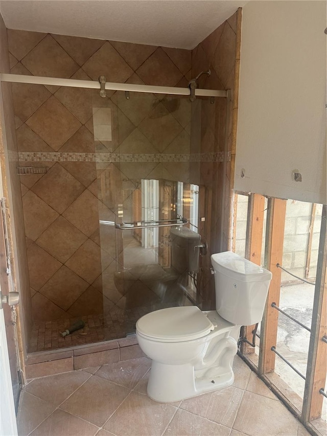 bathroom featuring tile patterned flooring, toilet, and walk in shower