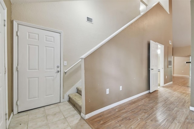 foyer entrance featuring light hardwood / wood-style floors and a high ceiling