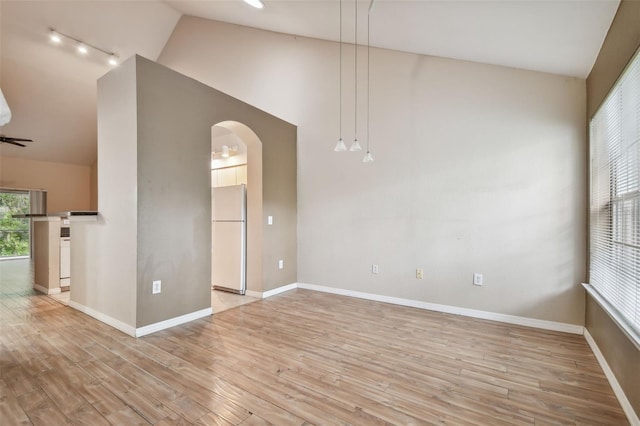 empty room with light hardwood / wood-style floors and vaulted ceiling