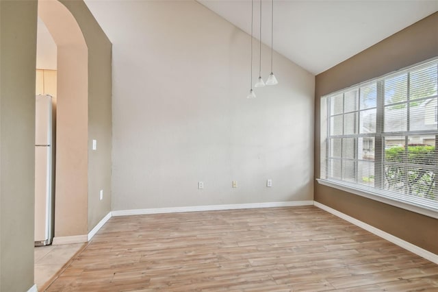 spare room with vaulted ceiling and light hardwood / wood-style flooring