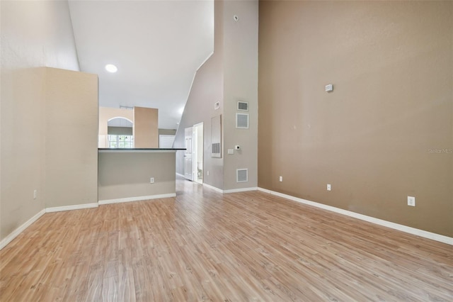 unfurnished living room featuring light hardwood / wood-style flooring and high vaulted ceiling