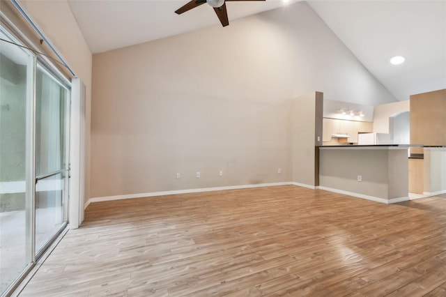 unfurnished living room featuring a healthy amount of sunlight, ceiling fan, light hardwood / wood-style floors, and high vaulted ceiling