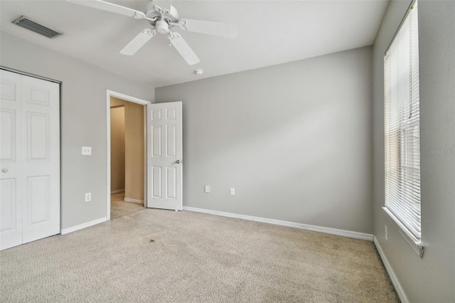 unfurnished bedroom featuring multiple windows, ceiling fan, a closet, and light carpet