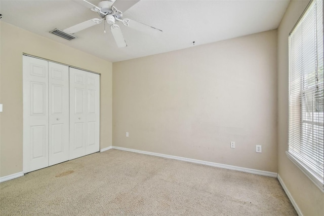 unfurnished bedroom featuring ceiling fan, a closet, and light colored carpet