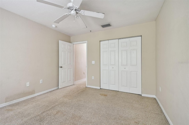 unfurnished bedroom featuring a closet, light colored carpet, and ceiling fan