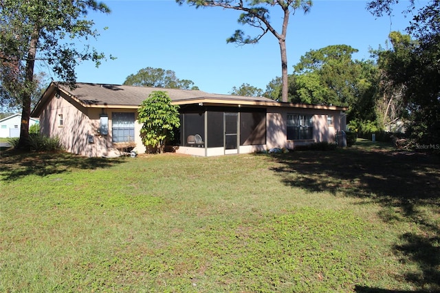 rear view of property with a lawn and a sunroom