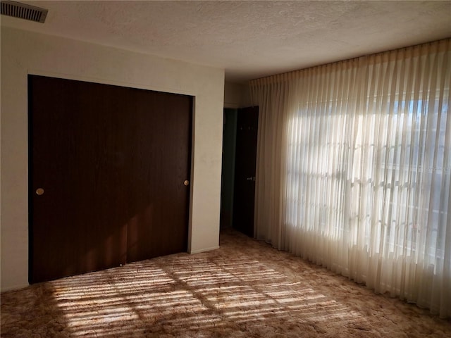 unfurnished bedroom with carpet, a textured ceiling, and a closet