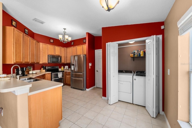 kitchen featuring appliances with stainless steel finishes, sink, washer and dryer, a chandelier, and lofted ceiling