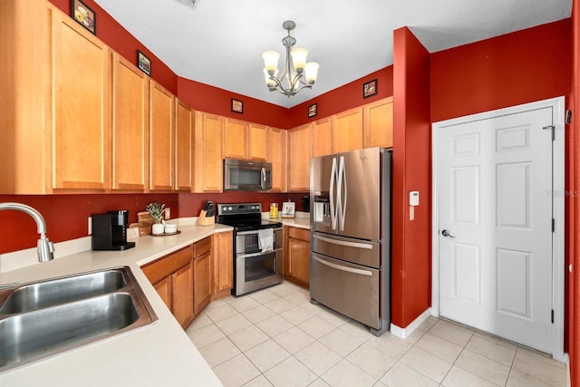 kitchen featuring stainless steel appliances, sink, light tile patterned floors, pendant lighting, and an inviting chandelier