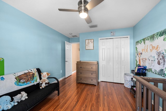 interior space featuring ceiling fan, dark hardwood / wood-style floors, a crib, and a closet