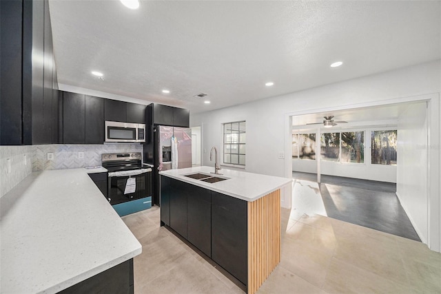 kitchen with a wealth of natural light, sink, a center island with sink, and appliances with stainless steel finishes