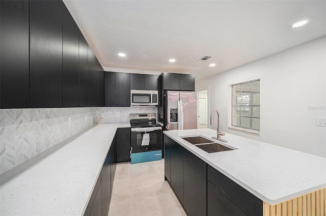 kitchen featuring tasteful backsplash, sink, an island with sink, and appliances with stainless steel finishes