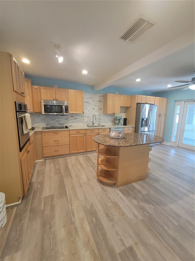 kitchen featuring sink, light hardwood / wood-style floors, decorative backsplash, a kitchen island, and appliances with stainless steel finishes