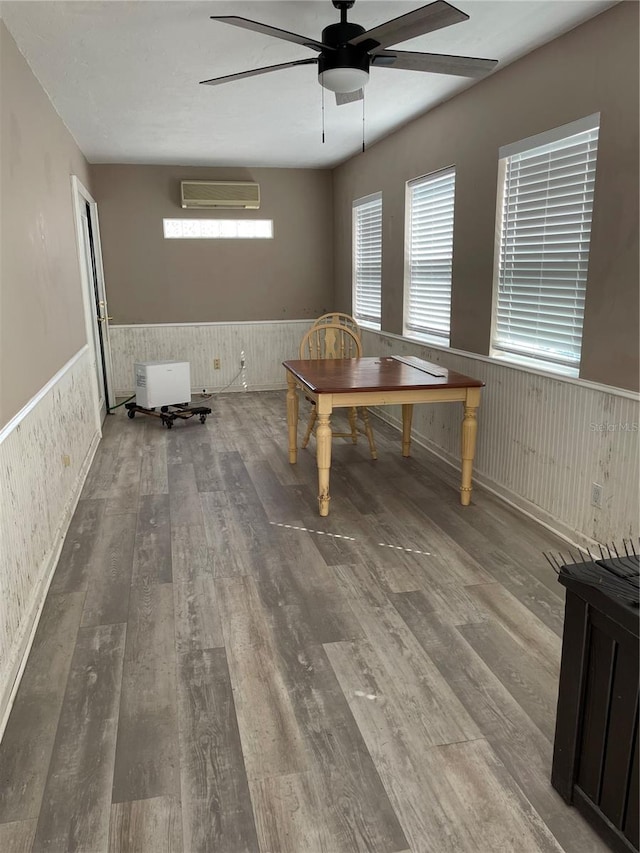 unfurnished dining area featuring ceiling fan, plenty of natural light, a wall mounted air conditioner, and hardwood / wood-style flooring