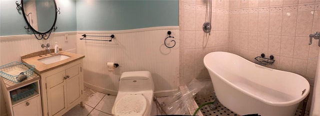 bathroom with tile patterned flooring, a washtub, toilet, and tile walls