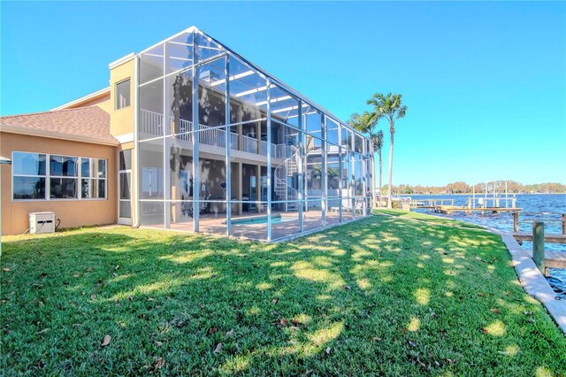 rear view of house featuring a lanai, a patio area, a yard, and a water view