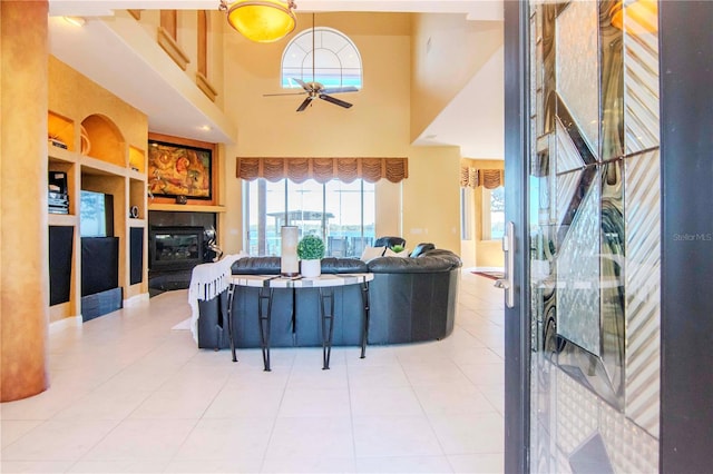 tiled living room with ceiling fan and a high ceiling