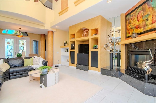 living room with tile patterned floors, built in shelves, a premium fireplace, and french doors