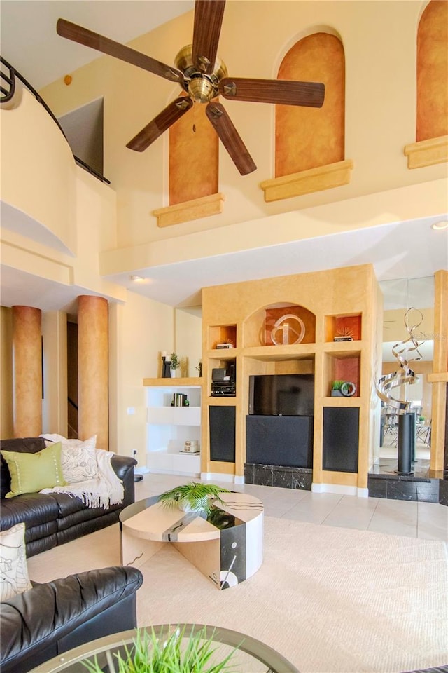 living room featuring a high ceiling, built in features, ceiling fan, and light tile patterned flooring