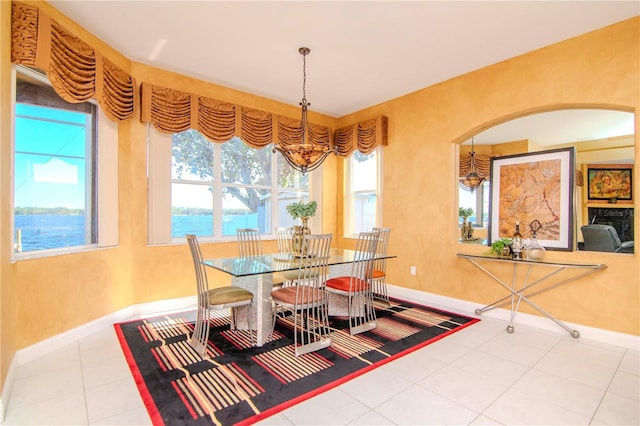 dining area with tile patterned flooring, a water view, and an inviting chandelier