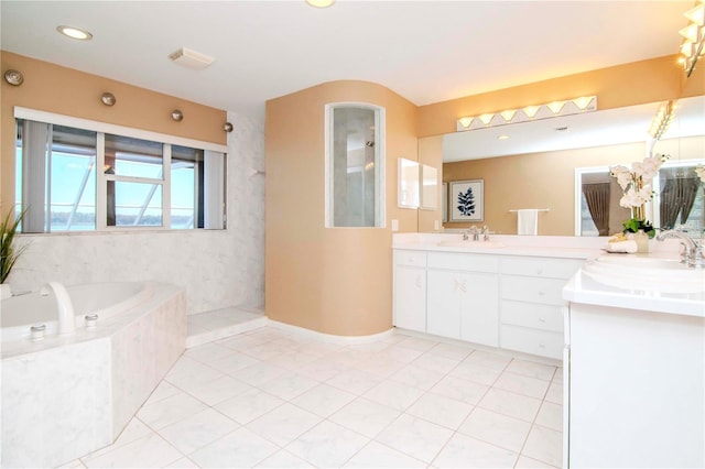 bathroom with tile patterned floors, tiled tub, and vanity