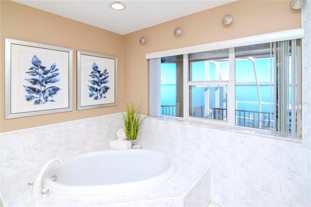 bathroom with a water view and tiled tub