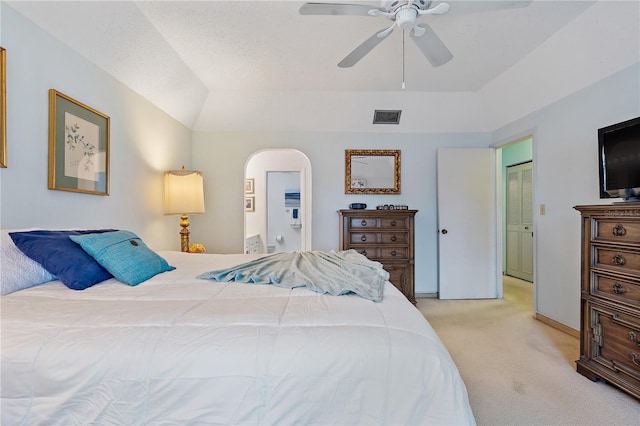 bedroom with light carpet, ensuite bath, ceiling fan, a closet, and lofted ceiling