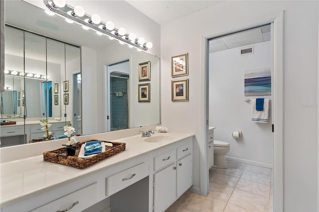 bathroom with tile patterned flooring, vanity, toilet, and walk in shower