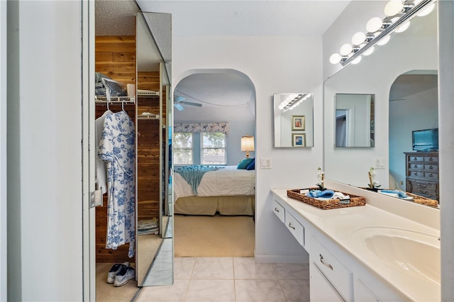 bathroom featuring tile patterned flooring, vanity, a textured ceiling, and wooden walls