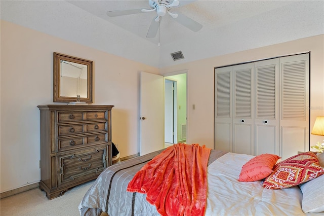 carpeted bedroom with a textured ceiling, a closet, vaulted ceiling, and ceiling fan