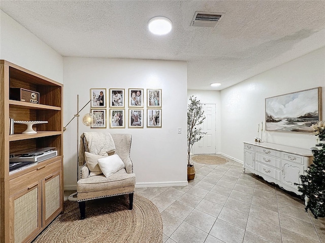 living area featuring a textured ceiling and light tile patterned flooring