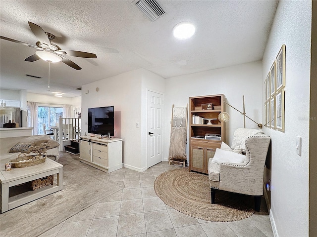 living room featuring light tile patterned floors, a textured ceiling, and ceiling fan