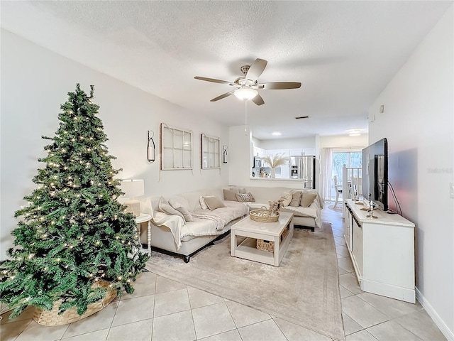 living room featuring ceiling fan, light tile patterned floors, and a textured ceiling