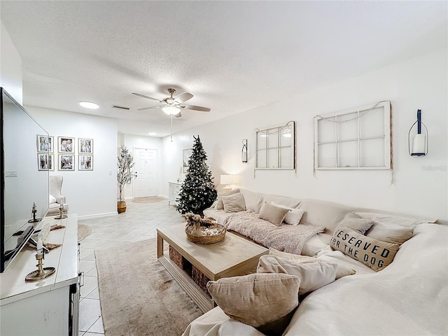 living room with a textured ceiling, ceiling fan, and light tile patterned flooring