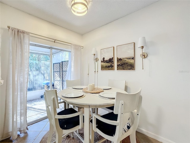 tiled dining room featuring a textured ceiling