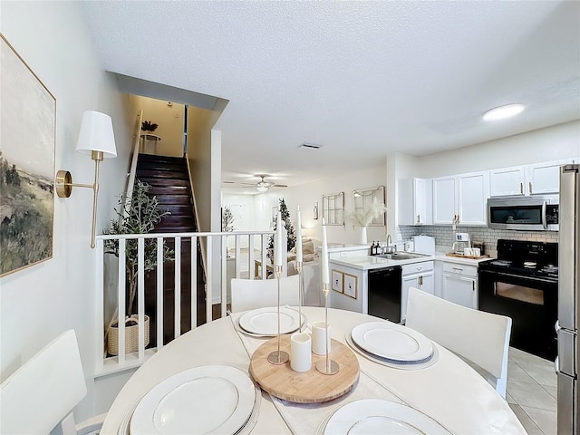 kitchen with backsplash, black appliances, ceiling fan, light tile patterned floors, and white cabinetry