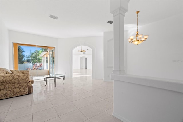 living room featuring ornate columns, light tile patterned floors, and ceiling fan with notable chandelier