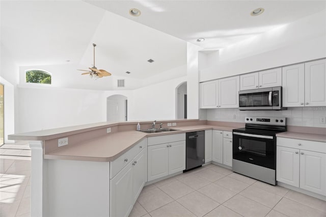 kitchen featuring kitchen peninsula, sink, vaulted ceiling, appliances with stainless steel finishes, and white cabinetry