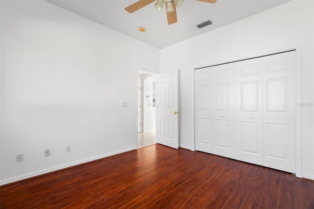 unfurnished bedroom with ceiling fan, a closet, and dark wood-type flooring