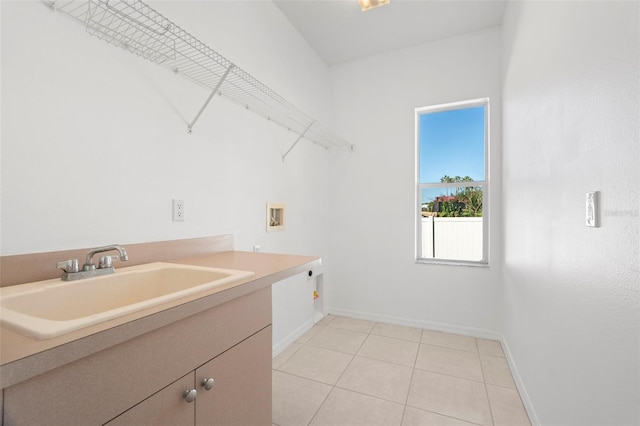 clothes washing area with cabinets, hookup for a washing machine, hookup for an electric dryer, sink, and light tile patterned floors