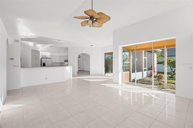 unfurnished living room featuring ceiling fan, light tile patterned floors, and lofted ceiling