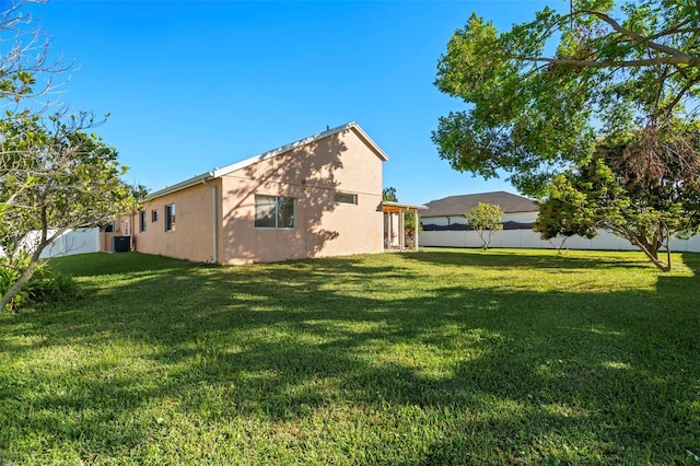 rear view of house featuring a lawn and central AC