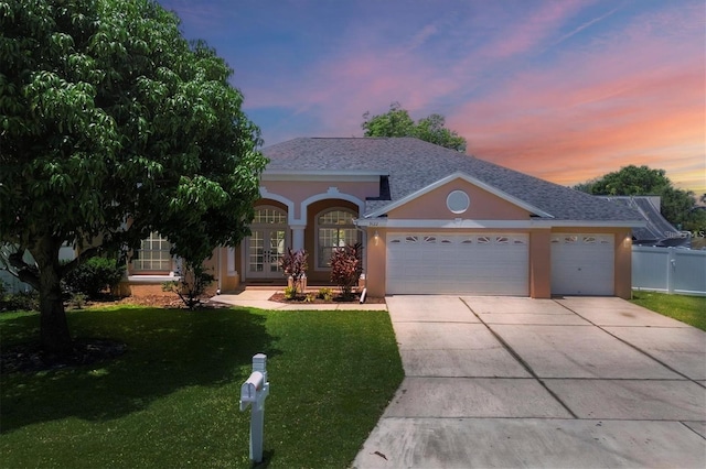 view of front facade with french doors, a garage, and a lawn