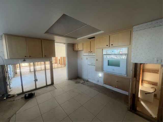 kitchen with light brown cabinets, oven, and light tile patterned flooring