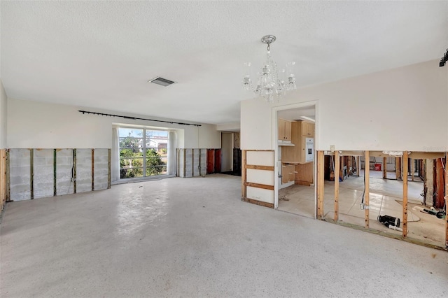 interior space featuring concrete flooring, a textured ceiling, and an inviting chandelier