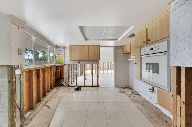 kitchen featuring light brown cabinetry, white oven, and light tile patterned floors