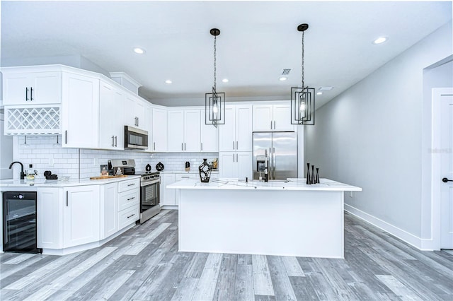 kitchen featuring white cabinets, wine cooler, a center island with sink, and appliances with stainless steel finishes