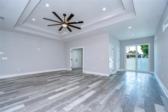 interior space featuring a tray ceiling, ceiling fan, and wood-type flooring