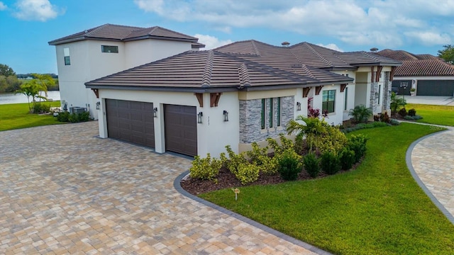 view of front of house with a front yard, a water view, and a garage