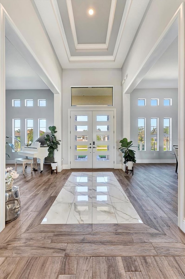 entryway featuring a tray ceiling, french doors, wood-type flooring, and ornamental molding